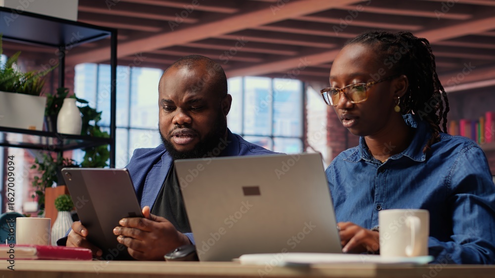 Poster smiling freelancers browsing the web on devices in a modern apartment, demonstrating a lifestyle of 