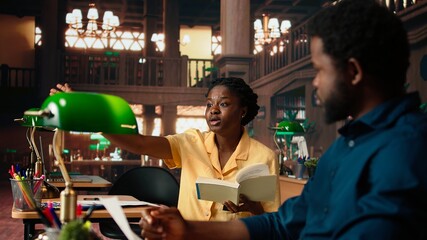 Diligent students reciting poetry together at the campus library, studying for a literature exam. Team of pupils showcasing productivity and commitment for self improvement. Camera A.