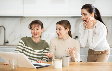 Women are reading email on laptop screen, cheering over good news, shouting triumphantly