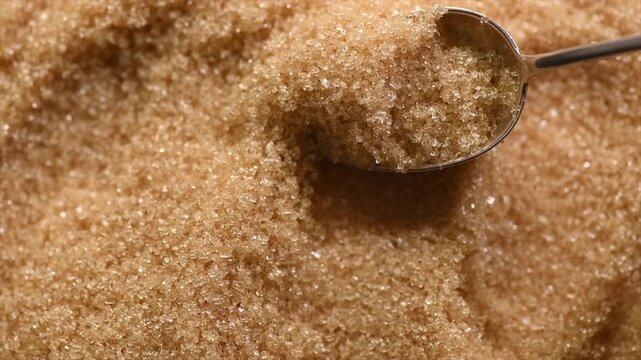Brown Cane sugar in a spoon close up. Brown sugar background. Heathy eating, diet concept. Top view, flat lay, slow motion