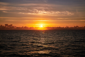 sunrise at sea behind clouds on a summer morning