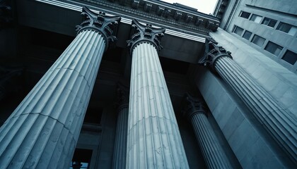 Low angle view of monumental stone columns on classical building facade. Ornate architectural details include fluted shafts, Corinthian capitals. Stone structure conveys power, stability, heritage in