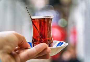 Hand holds a tulip shaped glass of Turkish black tea or chai, Istanbul, Turkey