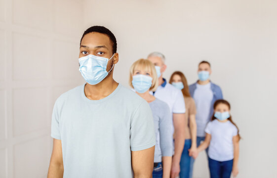 Young black guy in protective mask standing in line at hospital, waiting for vaccination against coronavirus, free space. Panorama. Covid-19 immunization, medical treatment concept