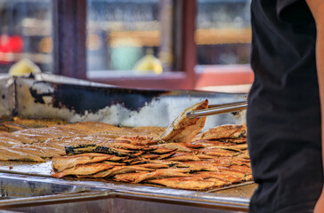 A cook uses tongs to grill fresh fish for Balik sandwiches on a boat in Istanbul