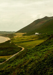 Obraz premium A scenic view of a coastal landscape with a winding road, a white house, and a mountain.