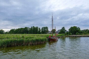 Traditional Sailboat at a Peaceful Riverside with Cloudy Sky - Wieck, Germany