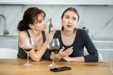 Sad woman sits silently in kitchen, female relative sympathize and comfort woman. Frustrated woman...