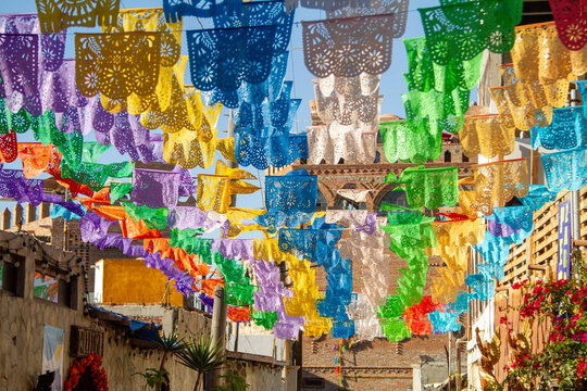 Looking up at a large group of colorful latin flags hanging against a blue sky