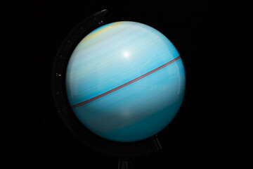 An earth globe scale rotating in high speed long exposure shot with black background and soft illumination