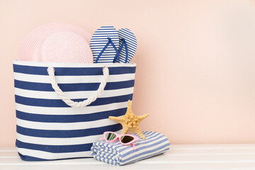Blue beach bag with summer accessories on wooden table