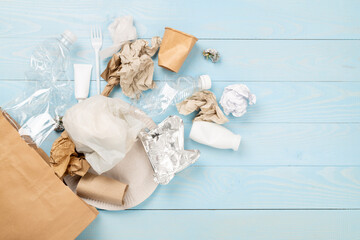 Bag with unsorted waste on wooden background, top view