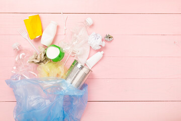 Bag with unsorted waste on wooden background, top view