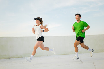 Joyful runners enjoying a vibrant morning jog on a rooftop overlooking the city skyline amid clear...