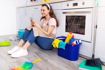 Taking break from house cleaning. Cheerful young housewife resting from domestic chores, using...