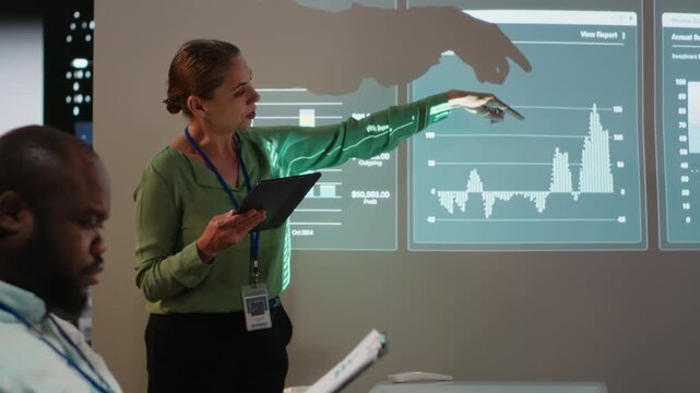 Business partners reviewing monthly data reports in night time meeting, developing internal communication strategies to ensure performance. Diverse team expanding a multinational company. Camera B.