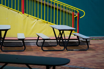 Metal picnic tables with integrated benches and yellow stairway cover