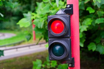 Red pole with mini traffic light showing red near playground