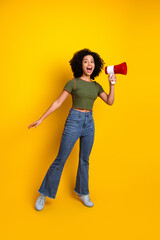 Young woman holding a megaphone on a vivid yellow background, expressing confidence and energy...