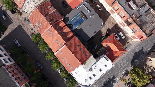Aerial vertical view of Klaipėda Old Town, Lithuania, showing cobblestone streets, red-tiled rooftops, historic buildings, and outdoor seating areas along narrow pedestrian-friendly lanes.
