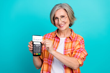Elderly Woman Smiling and Demonstrating a Payment Terminal with a Credit Card on a Vibrant...