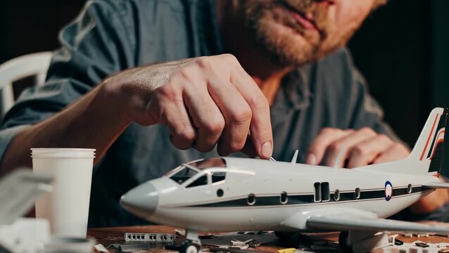 Caucasian Male Adult Assembling Model Airplane with Precision in Workshop