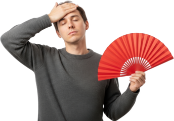 Young man in grey sweater fanning himself with a red fan showing discomfort from heat