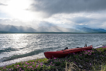 Red empty kayak by the shore of a river