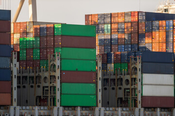Fototapeta premium Colorful Shipping Containers Stacked on Cargo Ships During Sunset