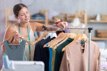 Girl seamstress shows finished dress. Small business, tailoring and creation of clothing, production