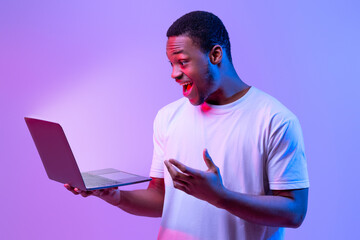 Online Offer. Surprised African American Man Holding Laptop Looking At Glowing Screen, Excited...