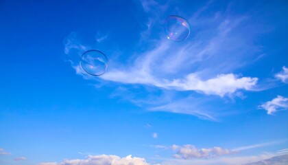 Two soap bubbles against a vibrant blue sky with wispy clouds