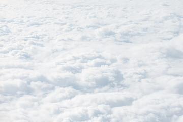 Aerial view of dense, fluffy white clouds forming a soft, layered expanse. Tranquil scene suggests...