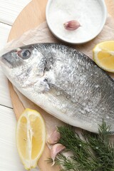 Fresh raw dourade with spices on white wooden table, closeup. Fish and seafood delicacies