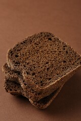 Pieces of fresh rye bread on brown background, closeup