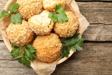 Delicious fried croquette balls with parsley on wooden table, top view