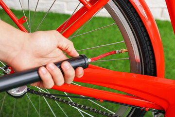 Man inflating bicycle tire with manual air pump indoors, closeup