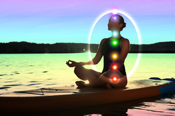 Woman meditating in Lotus pose on SUP board. Aura seen as bubble around her. Seven chakras glowing