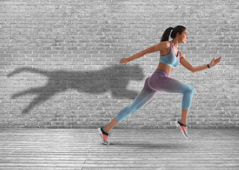Athletic young woman running. Her shadow in form of cheetah on brick wall. Sports poster © New Africa
