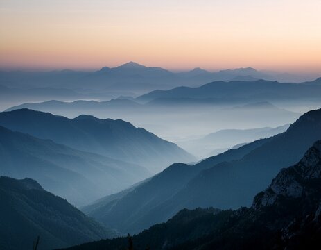 misty muted toned mountain range at dawn or dusk with hazy valleys and a soft pale sky