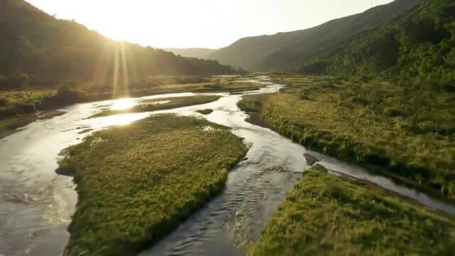 Winding river through a grassy valley bathed in sunlight