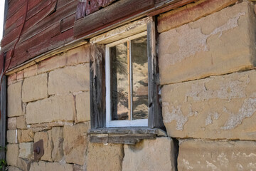 Wooden window frame with glass inset into a sandstone and wood structure.