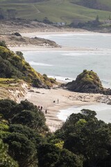 Hikers explore the scenic coastline of Tawharanui Regional Park, Warkworth, Auckland, New Zealand....