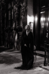 A Mysterious Figure Dressed in Black Stands on Dark and Sinister Street at Night