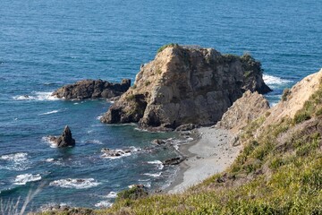 Coastal view of a rocky outcrop and pebble beach in Tawharanui Regional Park, New Zealand. Waves...