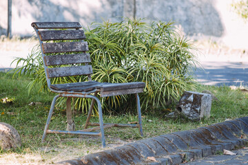 Old Weathered Wooden Chair in Grassy Park Beside Curb: Rustic Abandoned Outdoor Seating