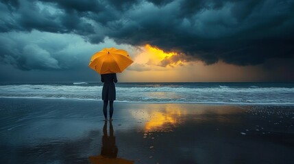 Person standing on wet beach holding bright yellow umbrella facing dramatic dark storm clouds with a glowing orange sunset breaking through over the ocean
