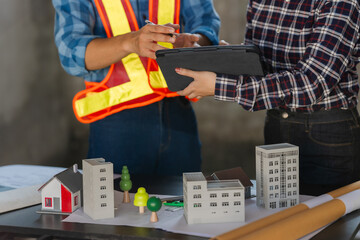 Engineers working on meeting blueprints to collaborate on projects with partners to create models...