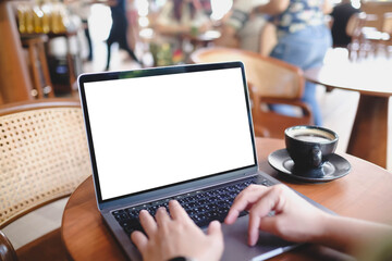 A person's hands typing on a laptop with a blank white screen in a busy, modern cafe. A versatile mockup for remote work or freelance concepts.