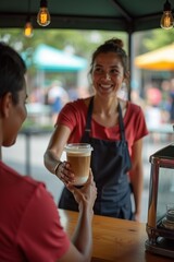 A barista handing iced coffee to customer at outdoor stall, friendly exchange captured in candid motion